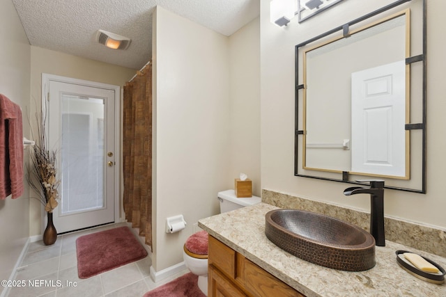 bathroom featuring tile patterned floors, a textured ceiling, toilet, and vanity