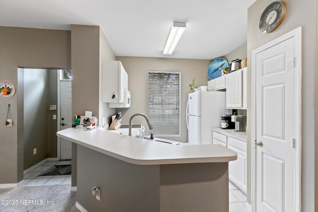 kitchen featuring kitchen peninsula, sink, light tile patterned floors, white cabinets, and white fridge