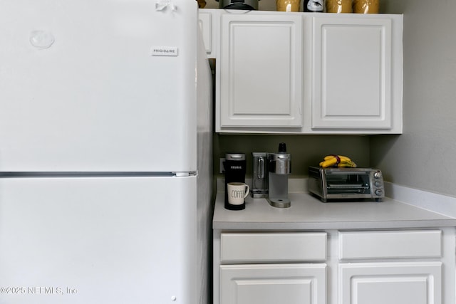 interior space featuring white fridge and white cabinetry