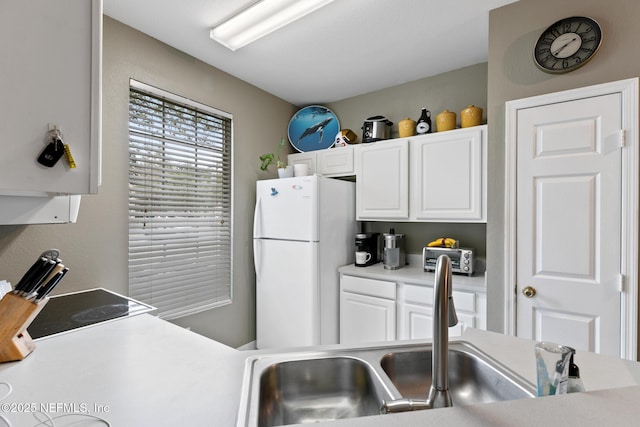 kitchen featuring white cabinetry, sink, and white refrigerator