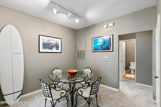 dining area featuring track lighting and light colored carpet