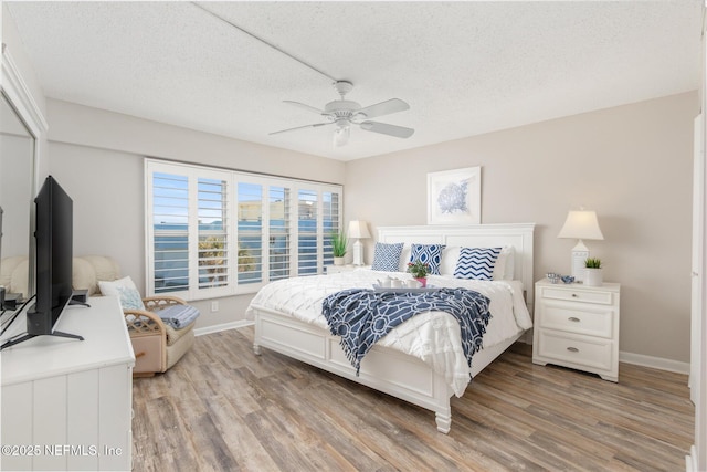 bedroom with light wood-type flooring, a textured ceiling, and ceiling fan