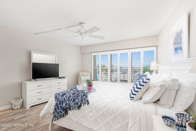 bedroom with ceiling fan, a textured ceiling, and light wood-type flooring