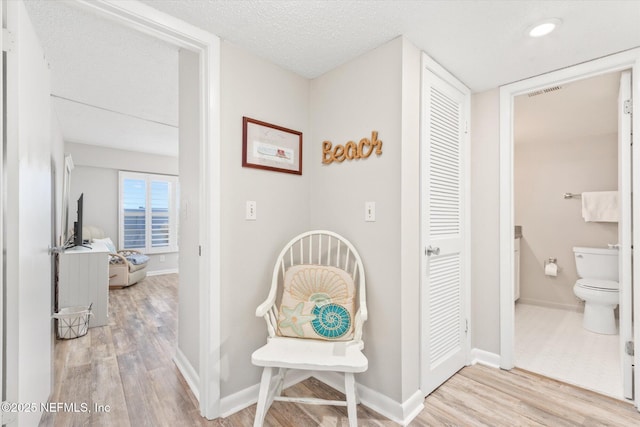 corridor with light hardwood / wood-style floors and a textured ceiling