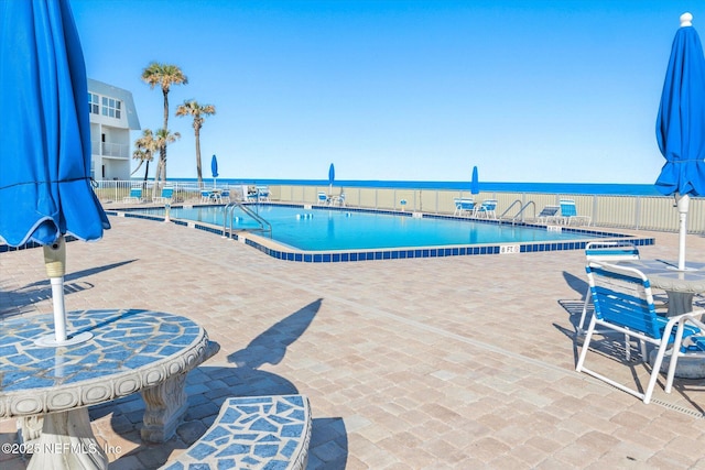 view of pool with a water view and a patio