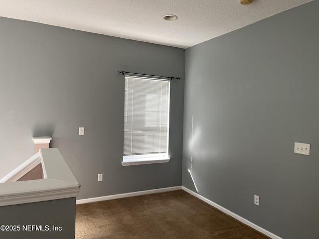 empty room featuring dark colored carpet and a textured ceiling