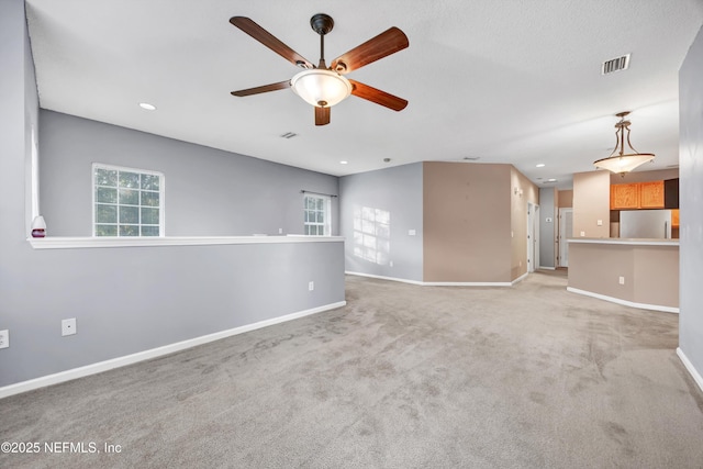 unfurnished living room featuring light colored carpet and ceiling fan