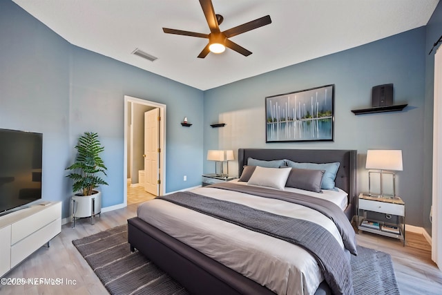 bedroom with connected bathroom, ceiling fan, and light hardwood / wood-style flooring