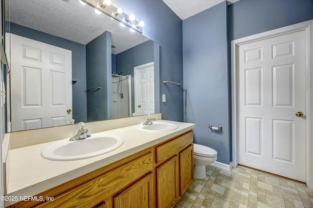 bathroom featuring vanity, a shower with shower door, a textured ceiling, and toilet