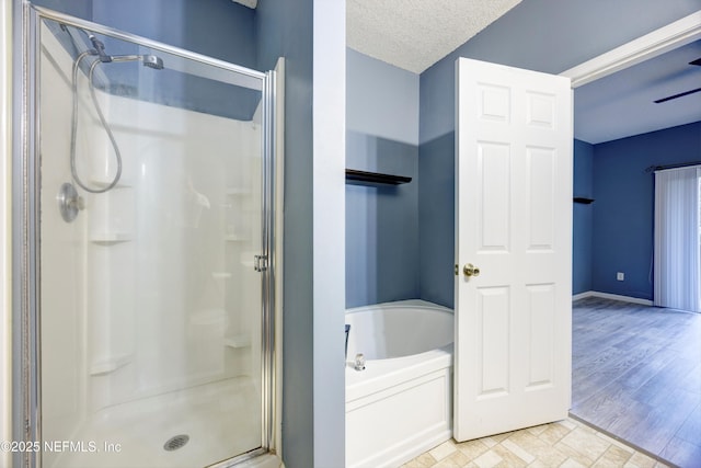 bathroom with hardwood / wood-style floors, ceiling fan, shower with separate bathtub, and a textured ceiling