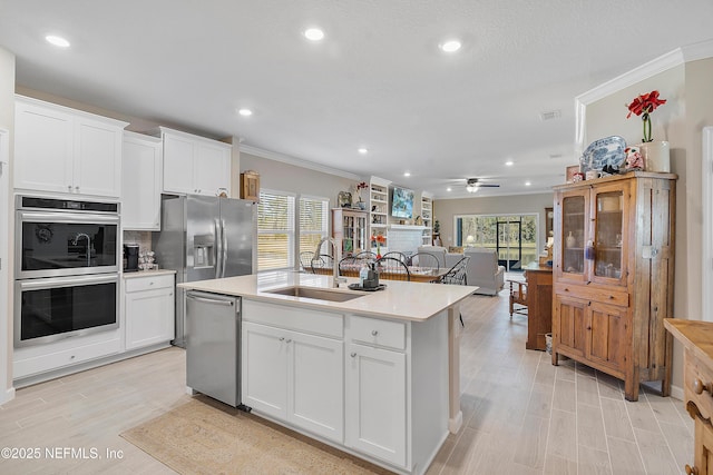 kitchen featuring white cabinets, appliances with stainless steel finishes, a center island with sink, and sink