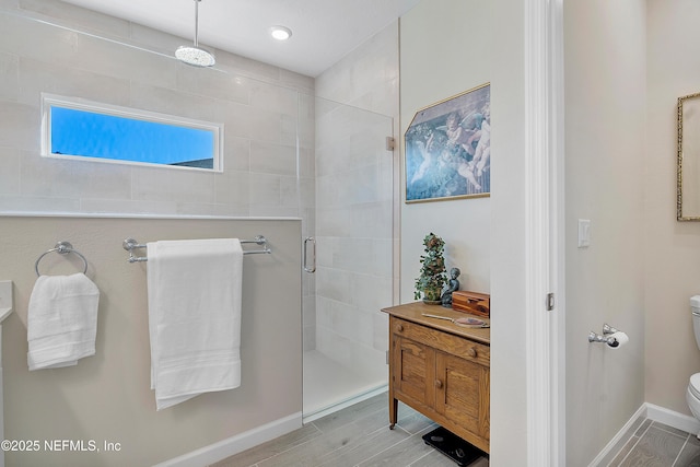 bathroom featuring a shower with door and toilet