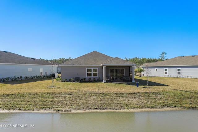 back of property with a yard, a water view, cooling unit, and a sunroom