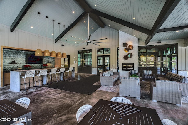 living room featuring concrete flooring, ceiling fan, beam ceiling, high vaulted ceiling, and a fireplace