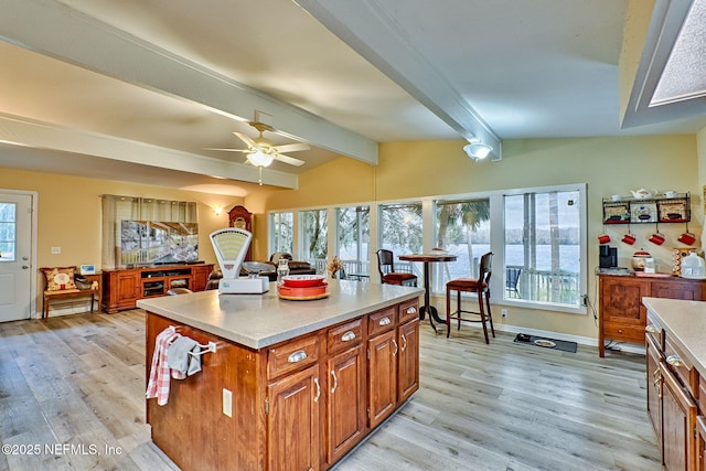 kitchen with lofted ceiling with beams, a center island, plenty of natural light, and ceiling fan