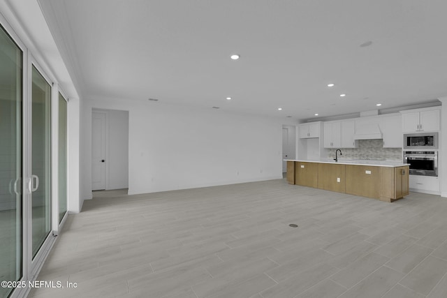 kitchen with built in microwave, a sink, stainless steel oven, tasteful backsplash, and open floor plan