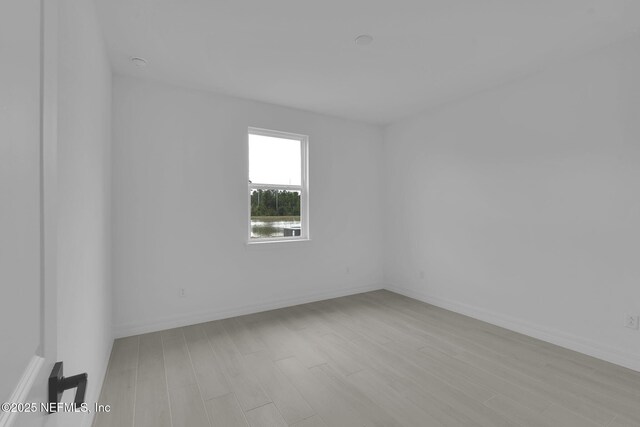 unfurnished room featuring baseboards and light wood-type flooring