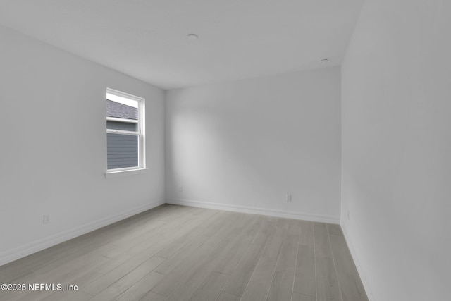 empty room featuring baseboards and light wood-style floors