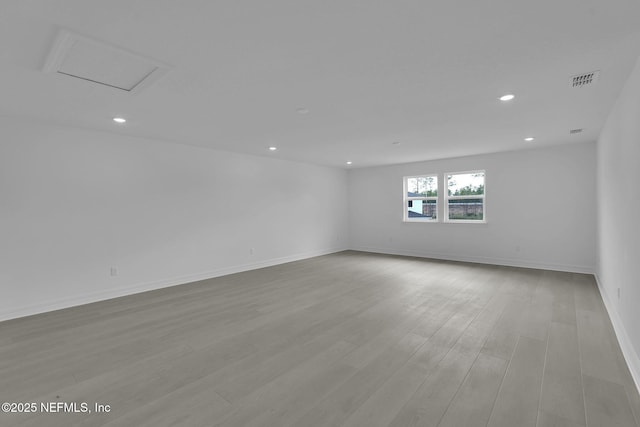 unfurnished room with attic access, light wood-style flooring, recessed lighting, and visible vents