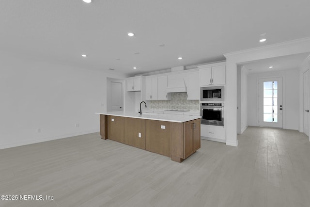 kitchen featuring light wood-type flooring, tasteful backsplash, white cabinetry, appliances with stainless steel finishes, and light countertops