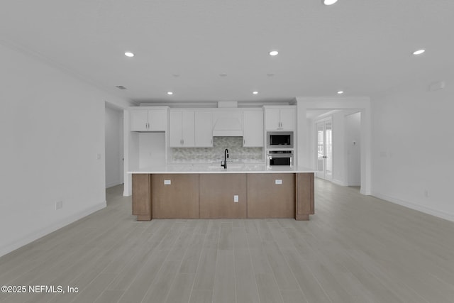 kitchen with built in microwave, white cabinetry, light countertops, and stainless steel oven