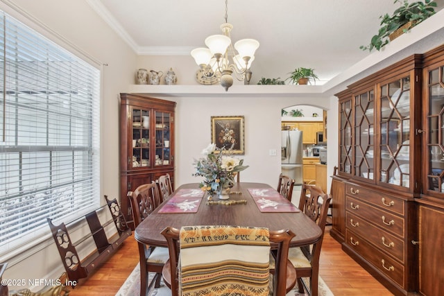 dining room featuring light wood-type flooring, crown molding, and a chandelier