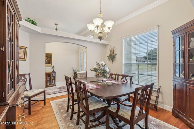 dining space with an inviting chandelier, crown molding, and light hardwood / wood-style flooring