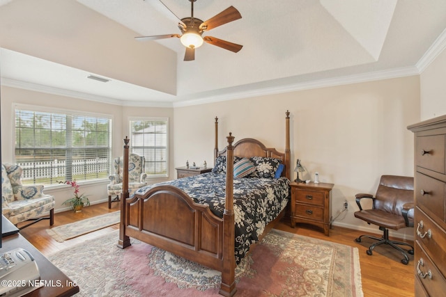 bedroom featuring ornamental molding, ceiling fan, a tray ceiling, and light hardwood / wood-style flooring