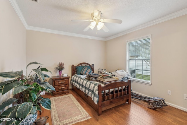 bedroom featuring wood-type flooring, a textured ceiling, ceiling fan, and crown molding