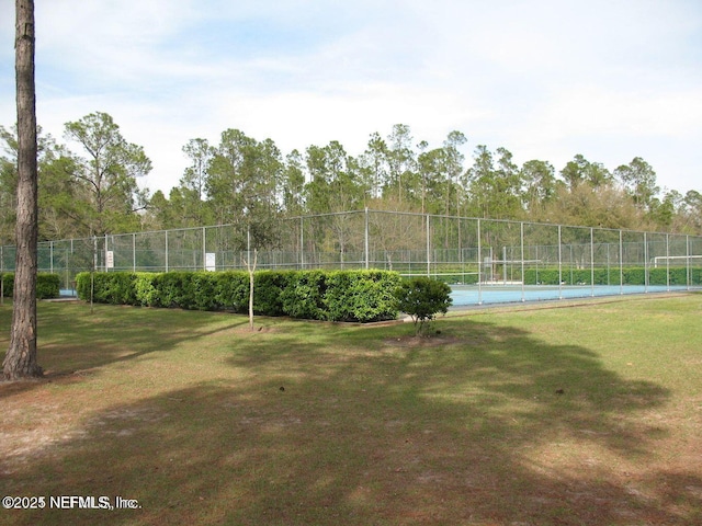 view of community featuring tennis court and a yard