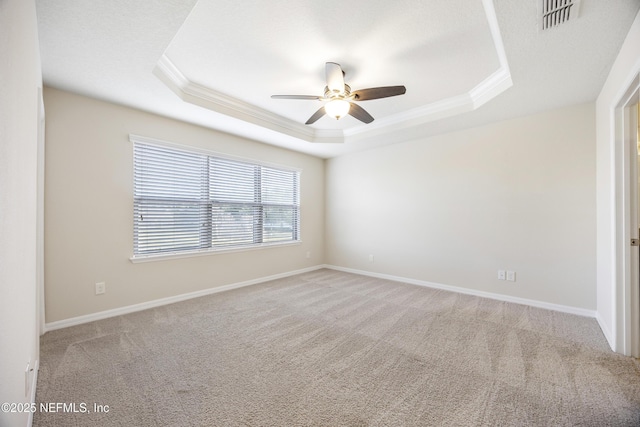 carpeted spare room featuring ceiling fan, ornamental molding, and a tray ceiling