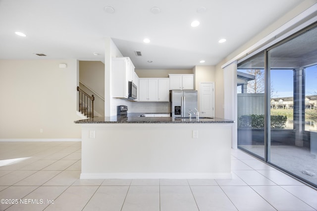 kitchen featuring dark stone counters, sink, black appliances, light tile patterned floors, and white cabinetry