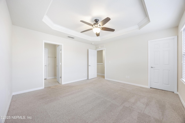 unfurnished bedroom featuring light carpet, a spacious closet, a raised ceiling, and ceiling fan