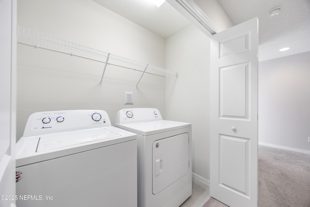 clothes washing area featuring light colored carpet and washing machine and clothes dryer