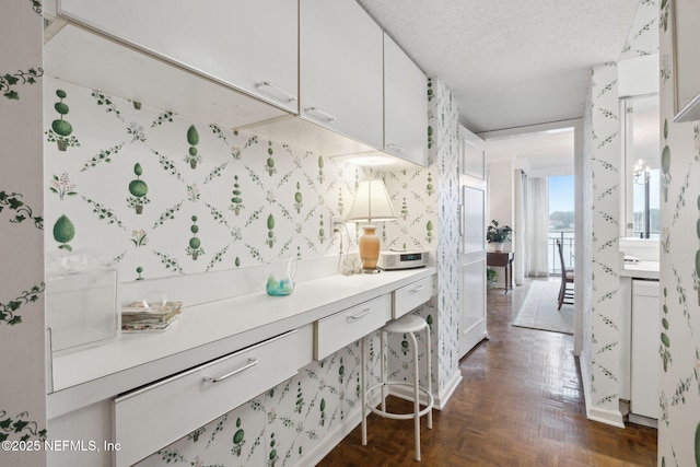 kitchen featuring a textured ceiling, dark parquet floors, and white cabinetry