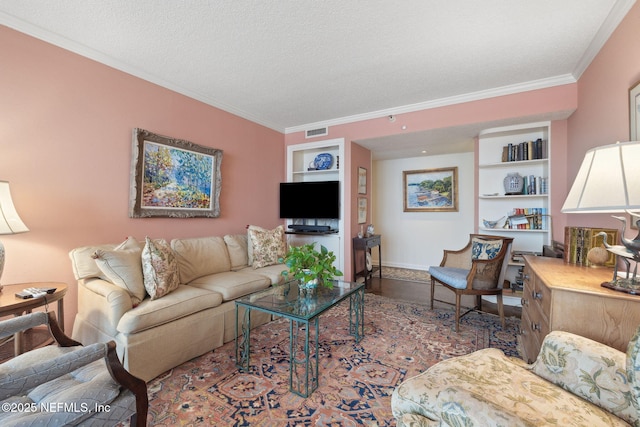 living room with built in shelves, a textured ceiling, and ornamental molding