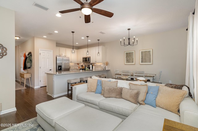 living room with ceiling fan with notable chandelier, sink, and dark hardwood / wood-style floors