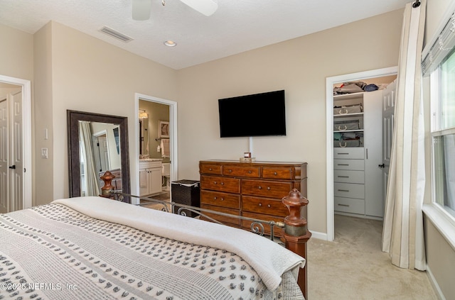 carpeted bedroom with ceiling fan, ensuite bathroom, a closet, and a walk in closet