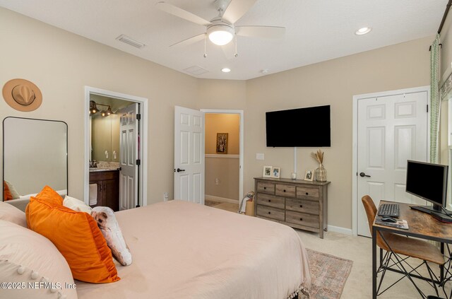 bedroom featuring light carpet, ceiling fan, and ensuite bath