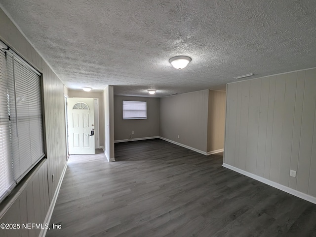 spare room featuring wooden walls and dark wood-type flooring