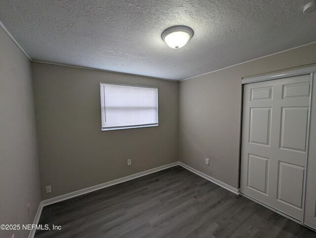 unfurnished bedroom with dark hardwood / wood-style flooring, a textured ceiling, and a closet