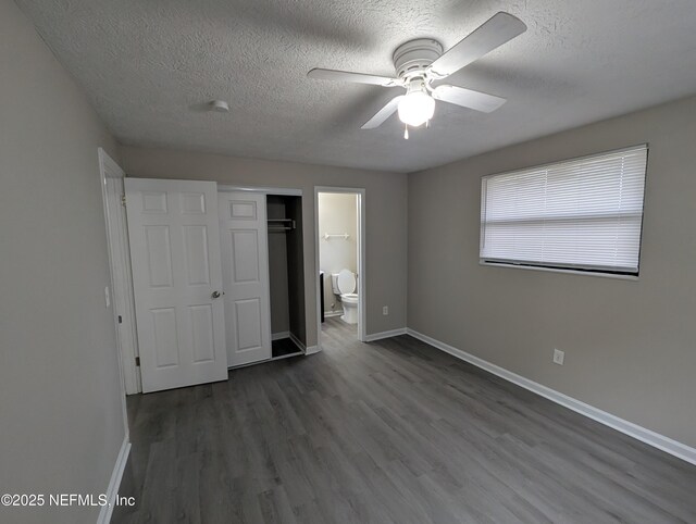 unfurnished bedroom featuring dark wood-type flooring, ensuite bath, ceiling fan, a textured ceiling, and a closet