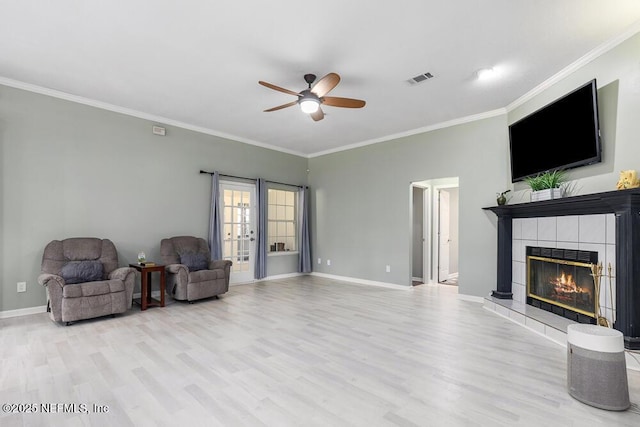 living area with a tile fireplace, french doors, ceiling fan, ornamental molding, and light hardwood / wood-style floors