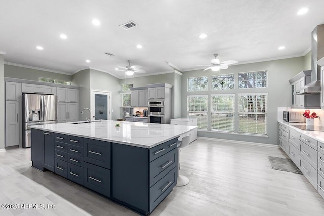 kitchen featuring a large island with sink, decorative backsplash, light hardwood / wood-style floors, and appliances with stainless steel finishes