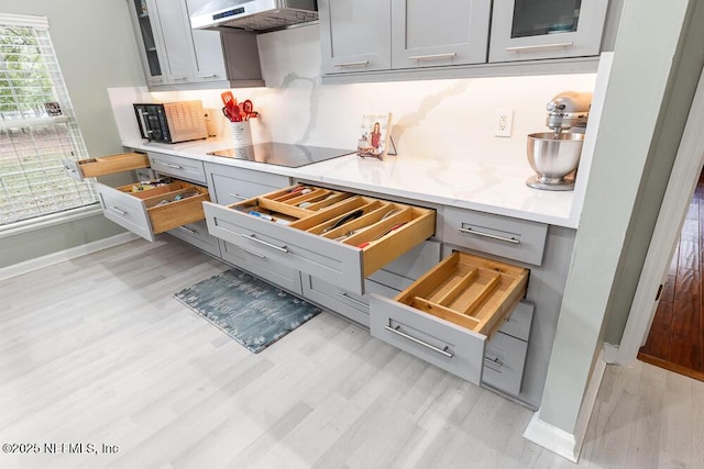 kitchen with black appliances, gray cabinets, exhaust hood, and light wood-type flooring