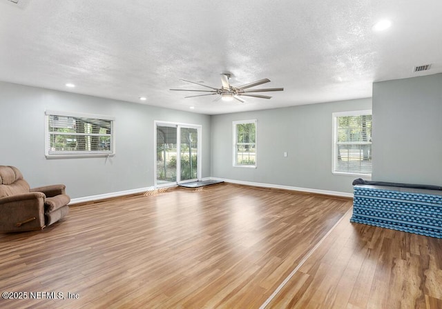 living room featuring a textured ceiling, light wood-type flooring, and a healthy amount of sunlight