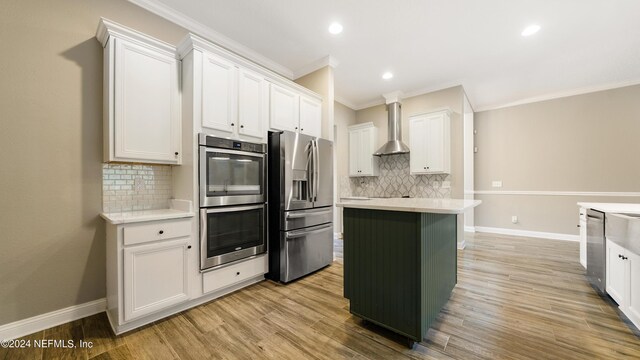 kitchen featuring decorative backsplash, white cabinetry, wall chimney exhaust hood, and stainless steel appliances