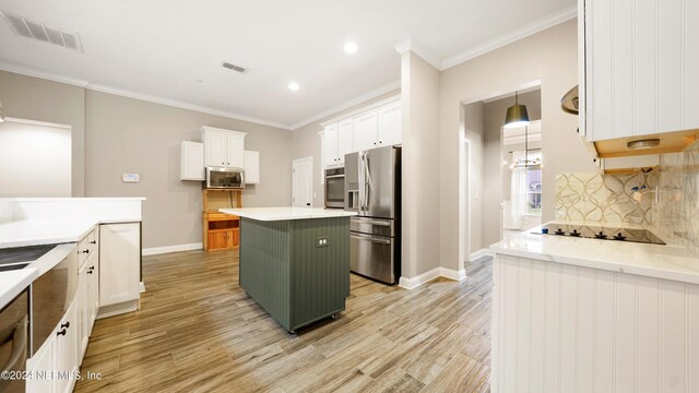 kitchen with decorative backsplash, a kitchen island, white cabinetry, and appliances with stainless steel finishes