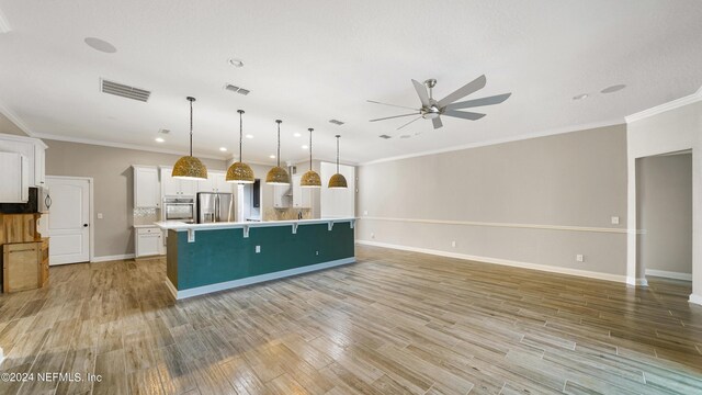 kitchen with appliances with stainless steel finishes, ceiling fan, a spacious island, white cabinetry, and hanging light fixtures