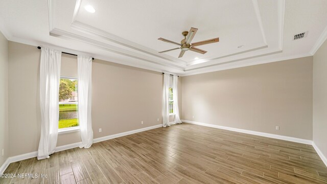 empty room featuring a raised ceiling, ceiling fan, and ornamental molding